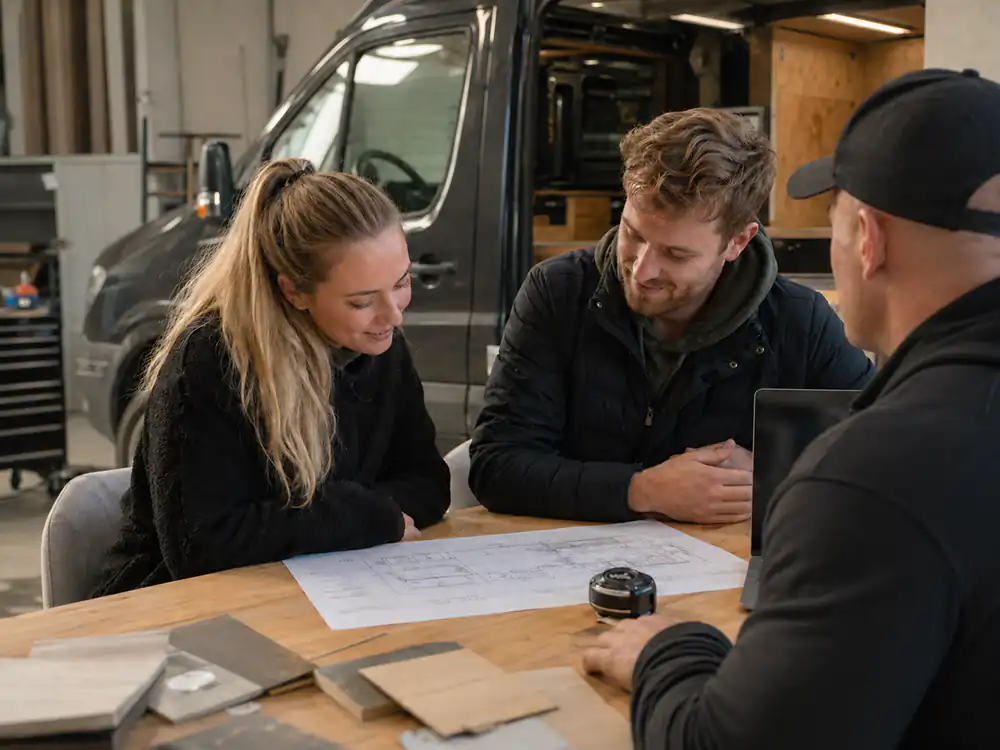 Elite RV team discussing a custom campervan floor plan with customers