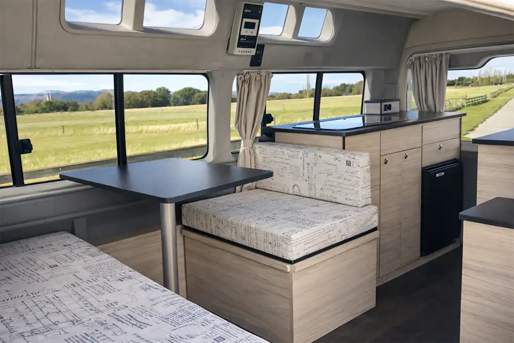 Custom campervan layout with seating, table, kitchen and storage