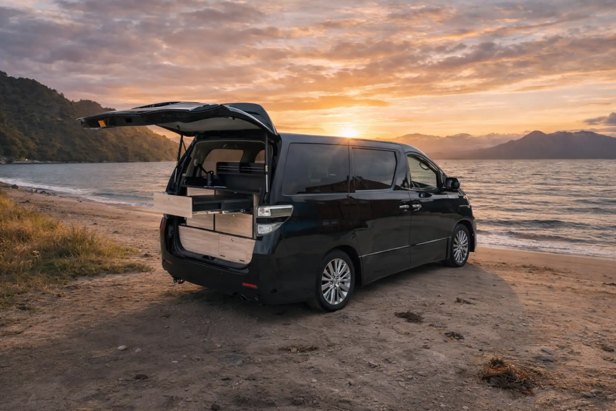 Compact campervan set up beside a New Zealand beach at sunset