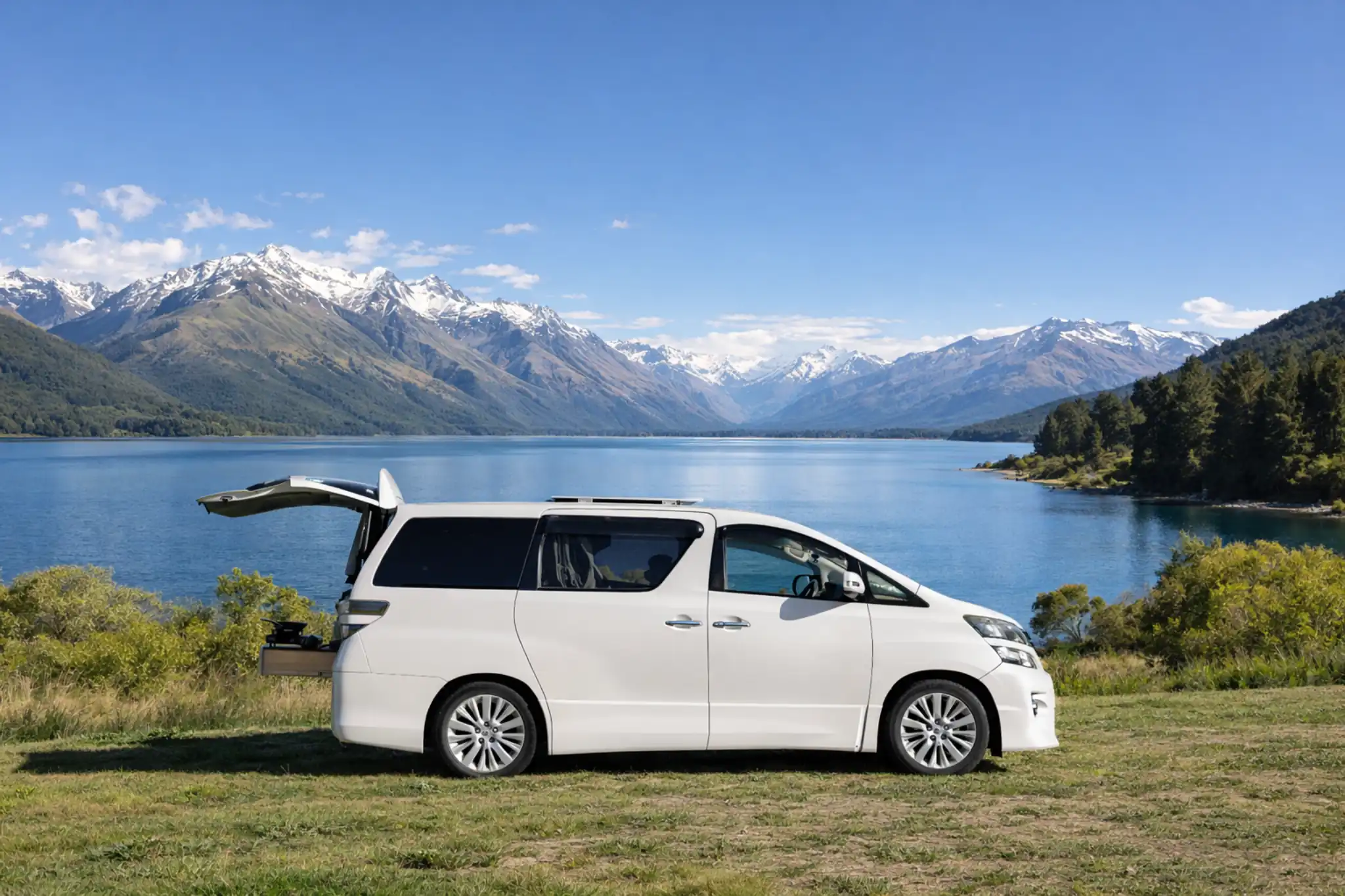 Compact campervan parked beside a mountain lake in New Zealand